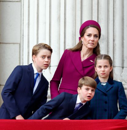 Prince George, Princess charlotte, Prince Louis, Kate Middleton and Prince William leaning to the right looking at planes from the palace balcony