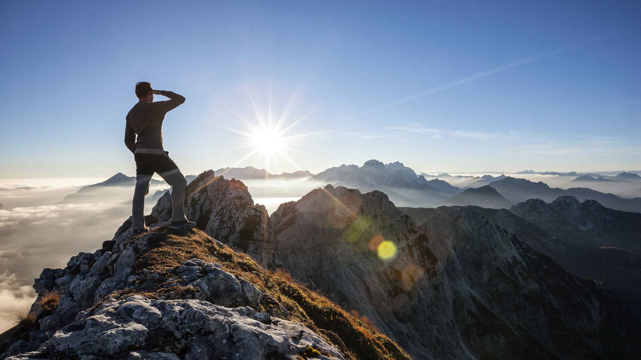 A man climbs to the top of a mountain.