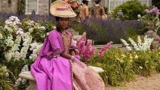 Arsema Thomas as Young Agatha Danbury wearing a bright pink dress with a paisley pattern.