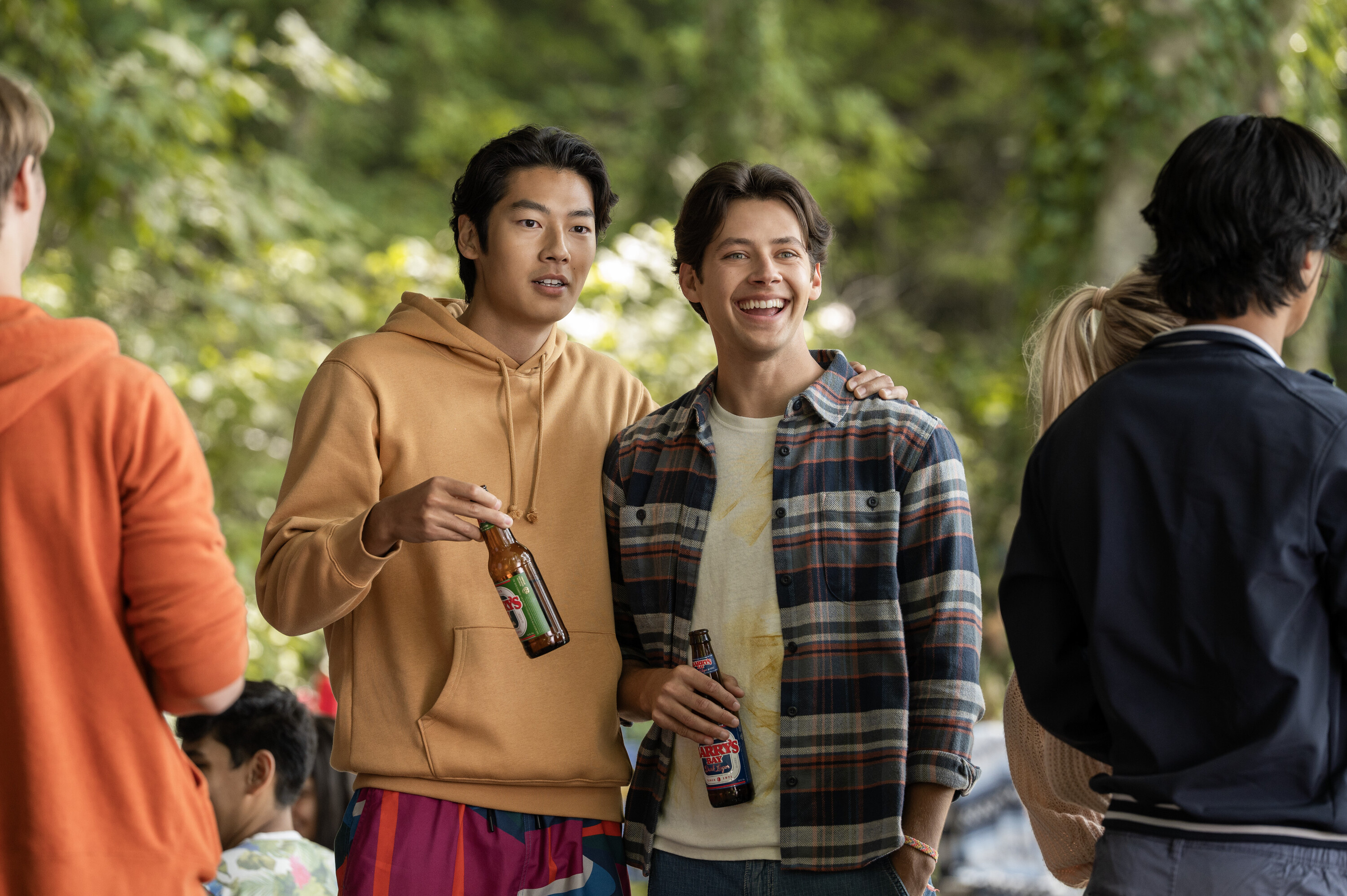 Joseph Chiu as Jordie in an orange sweatshirtand Matt Cornett as Sam in a plaid shirt drinking beers in a party scene from 'Every Year After.'