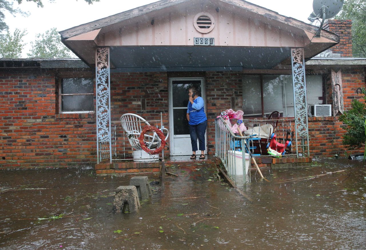 A woman on cellphone calls for help at her flooded residence in Lumberton, North Carolina, on September 15, 2018 in the wake of Hurricane Florence.