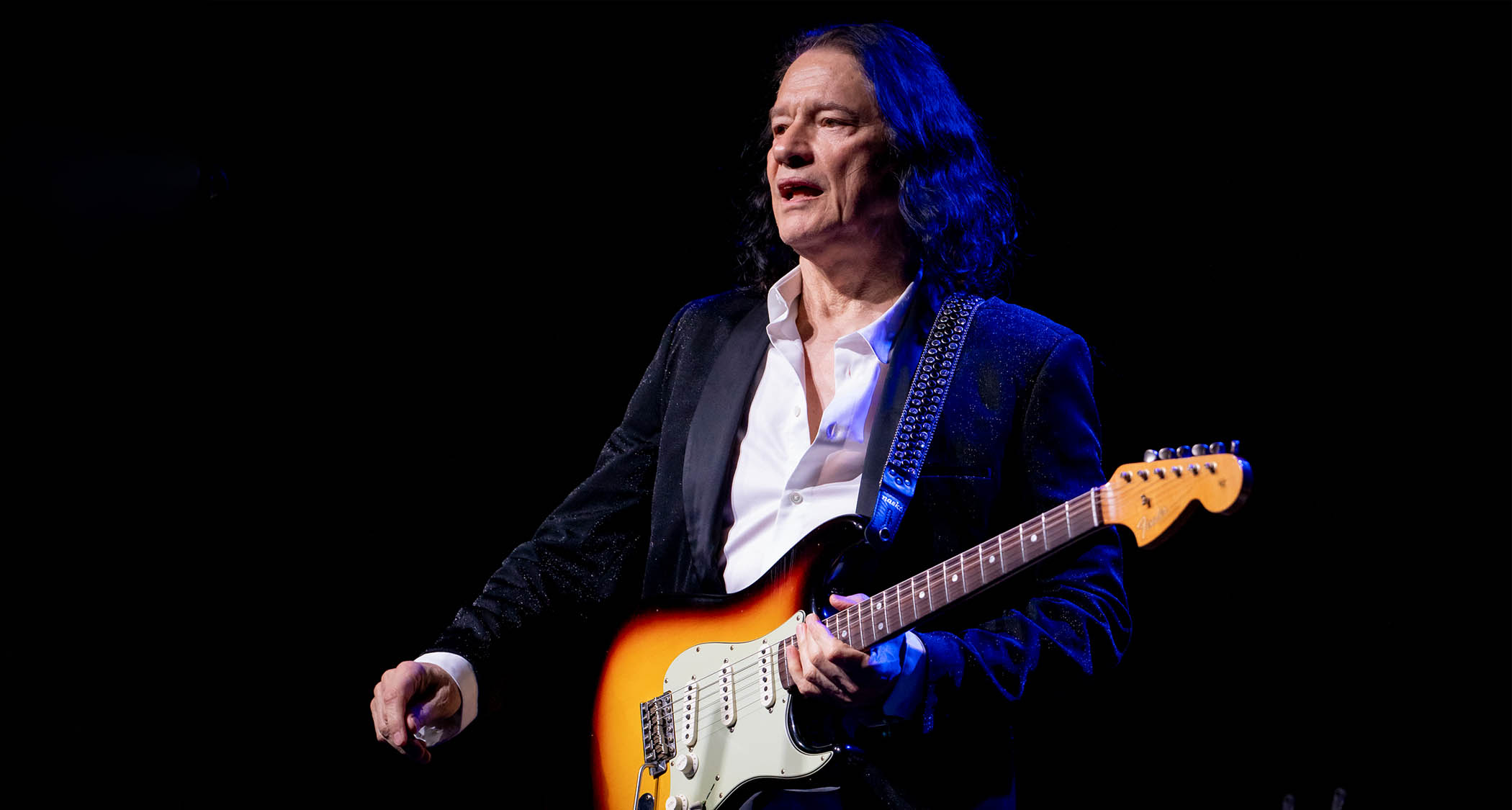 Robben Ford plays his 3-Color Sunburst Strat on a darkened stage.
