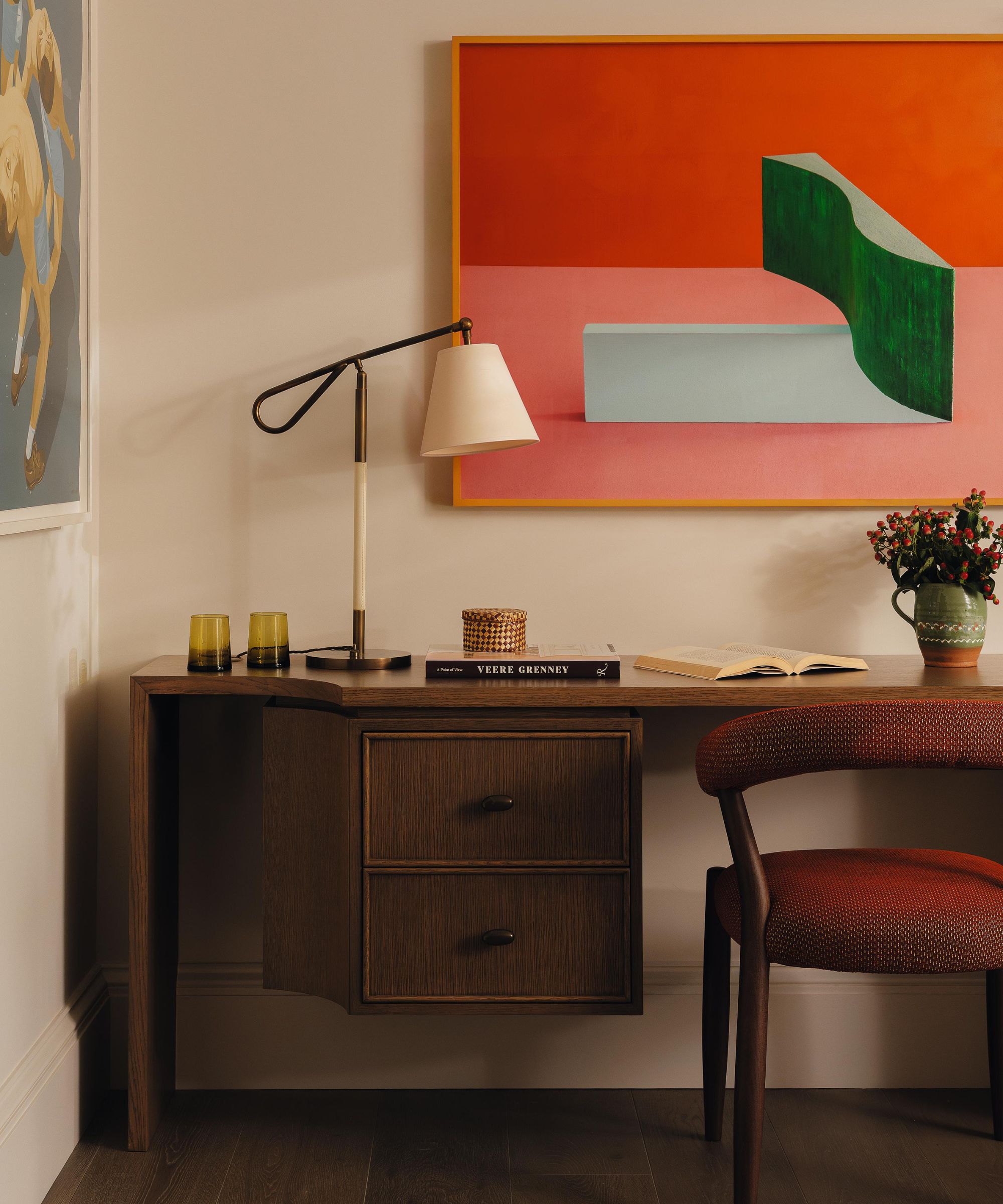a neutral study with large abstract artwork and a dark wooden desk