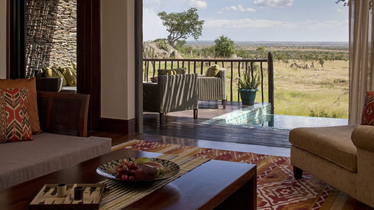 Image of a living room that opens to an outdoor balcony with a pool