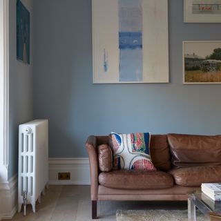 A sky blue-painted living room with a dark brown leather sofa