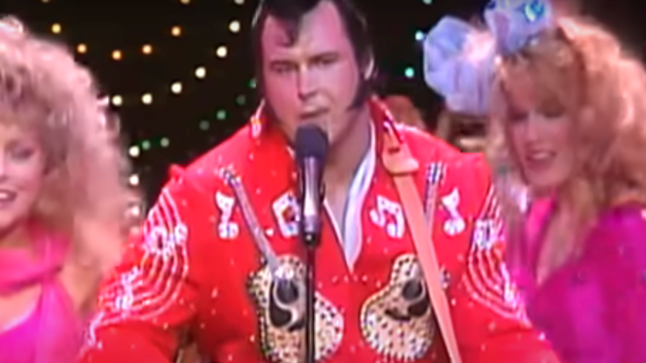 Honky Tonk man sings and plays his guitar surrounded by women.