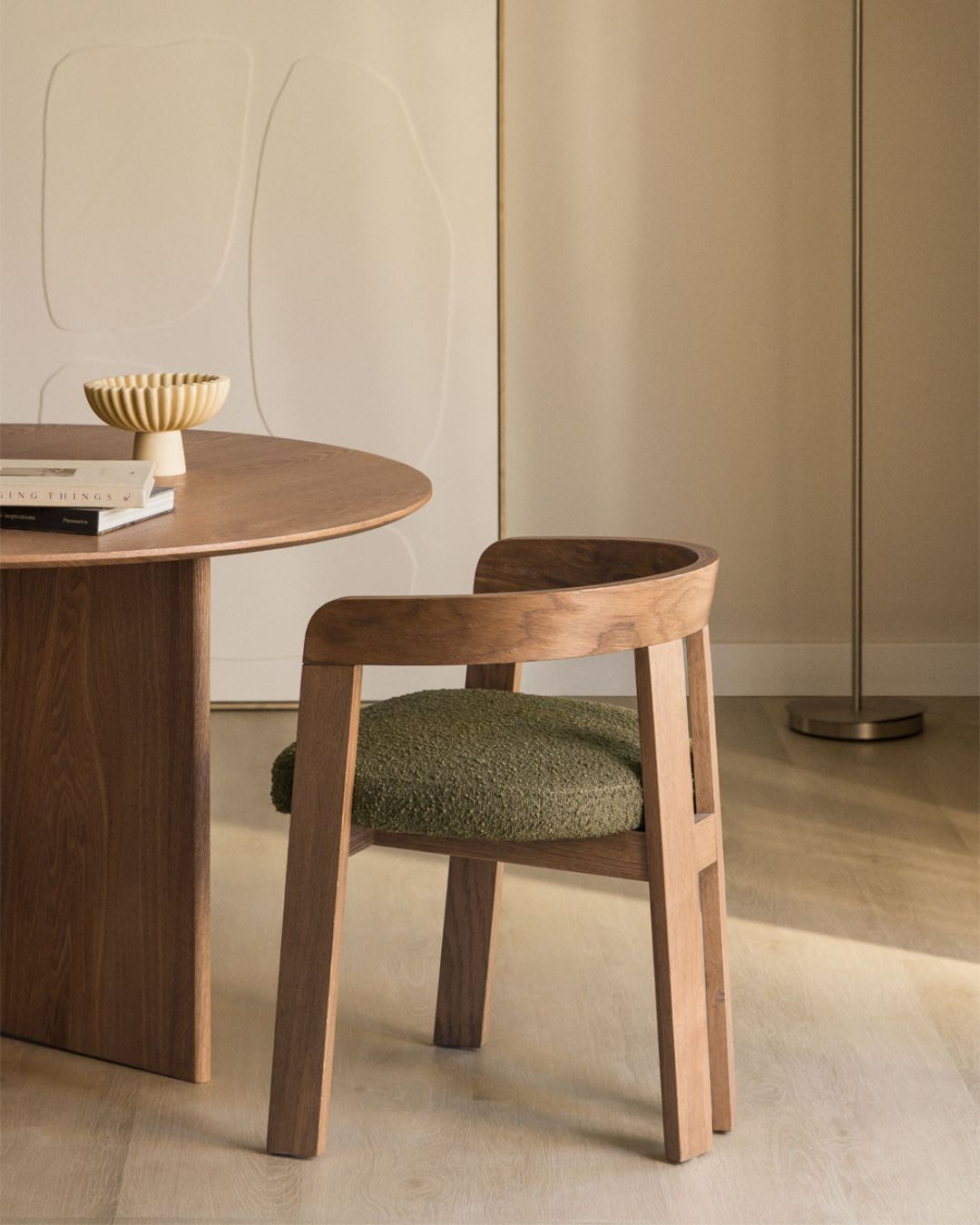 Yvone Upholstered Dining Chair With Armrests and Oak Wood against pale wood.