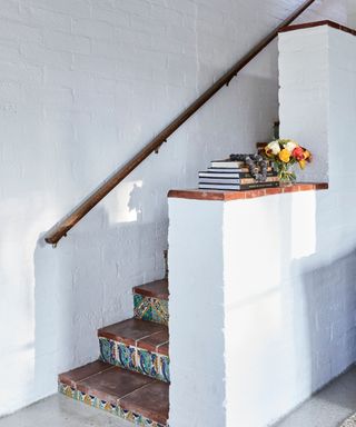 stairs with patterned tiles in Mediterranean style home with whitewashed walls