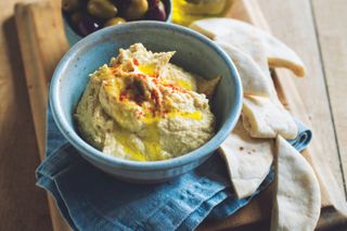Bowl of hummus with pitta bread and olives