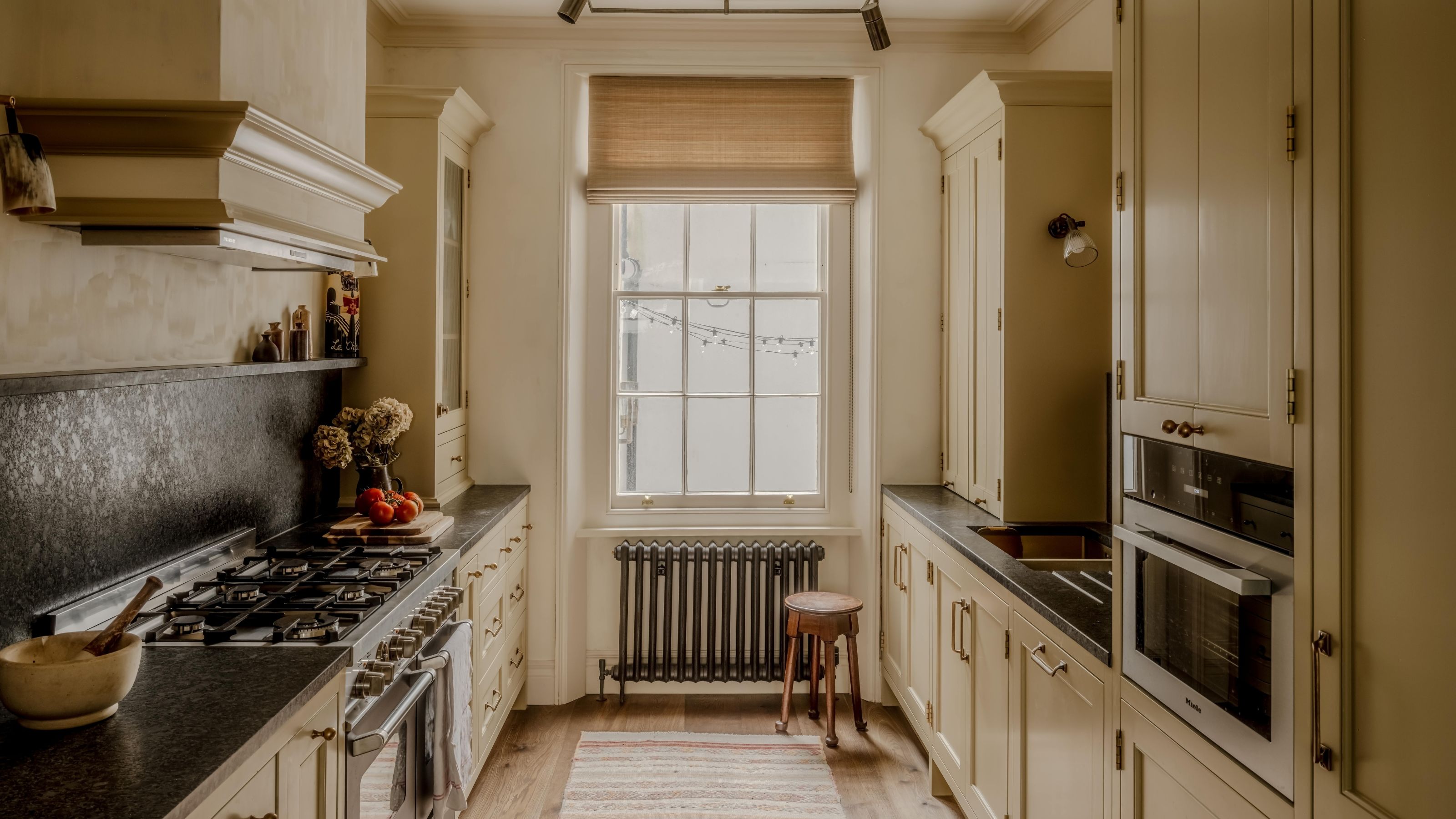 a warm butter yellow kitchen in a London townhouse with georgian window and dark countertops