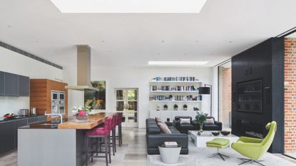 open plan diner and kitchen minimalist with stone floors sectional couch and kitchen island with purple bar stools