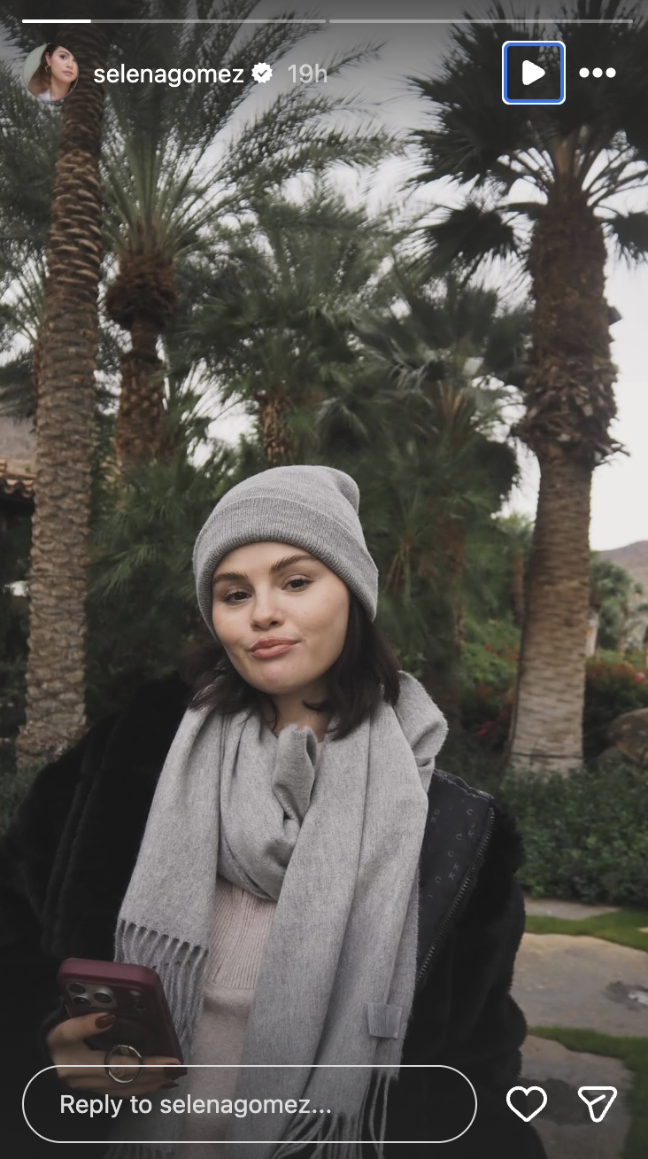 Selena Gomez wearing a grey beanie and scarf. Her bob haircut is peeking from underneath it.