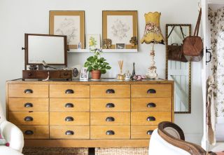 A set of reclaimed vintage drawers with wooden framed wall art, and lampshade lighting fixture