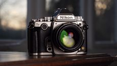 Nikon Df DSLR camera on a wooden surface by large window, with dusk light