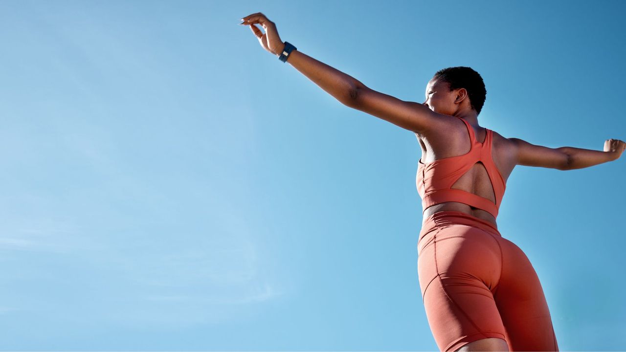 How to get toned arms: A woman in working kit against a blue sky