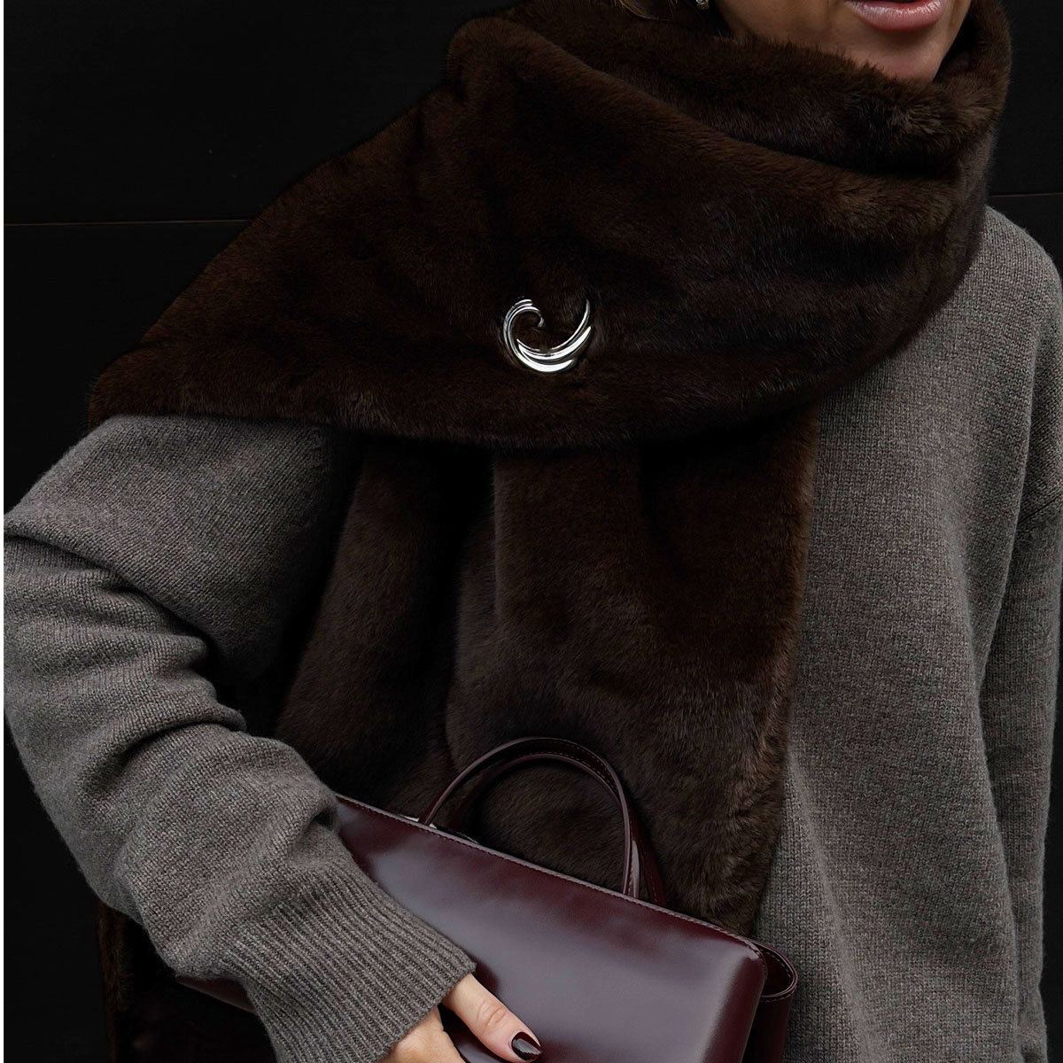 Woman in a gray sweater, brown faux-fur scarf, and burgundy bag