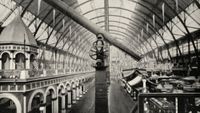 A black and white photo of a telescope on a very tall pedestal at a fair.