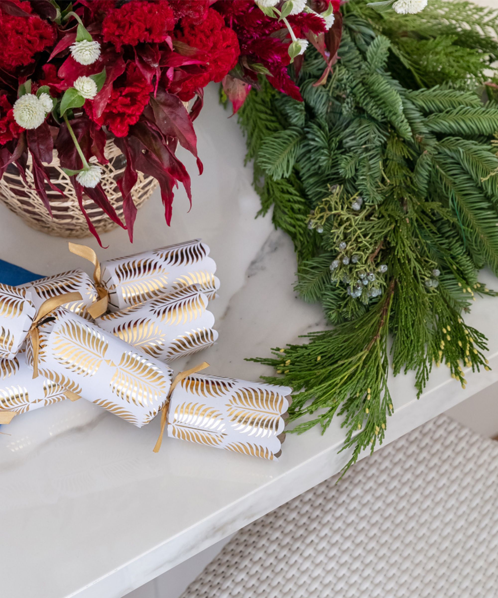 Crackers, greenery and red flowers on a marble kitchen counter