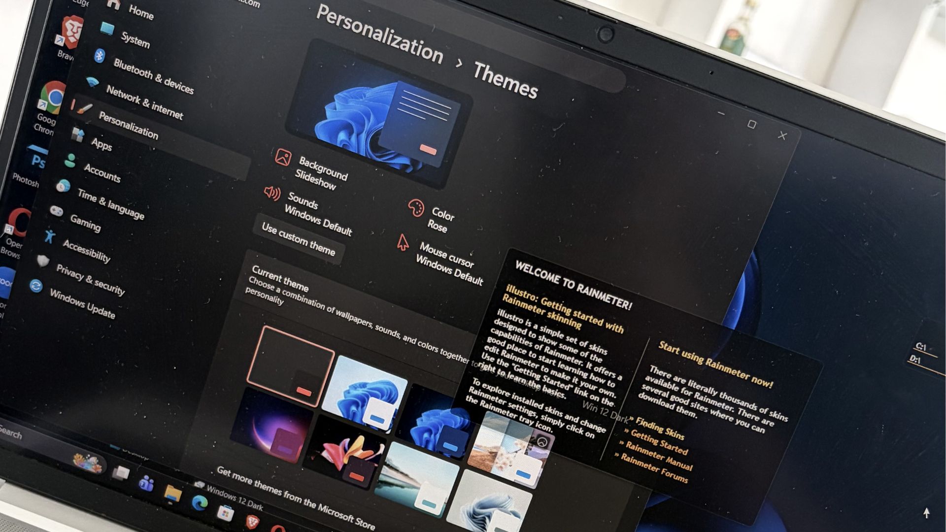 Close-up of a laptop screen displaying the Windows Personalization Themes menu. Multiple theme options are visible, conveying a tech-focused feel.