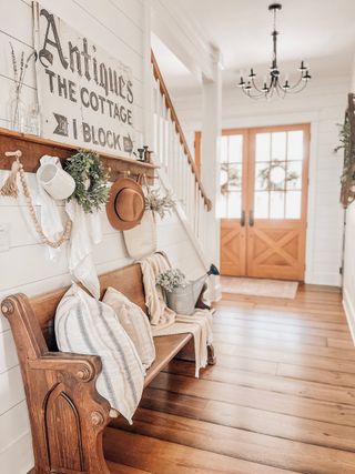 Country entryway bench with church pew dressed up with cushions, wooden floors and glass paneled door
