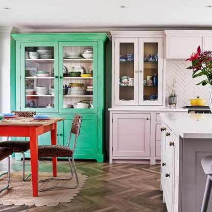 Kitchen with dressers painted green and pink, and a red painted kitchen table