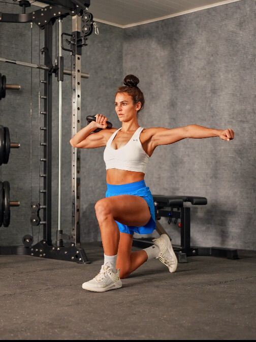 Woman exercises with kettlebell in gym setting