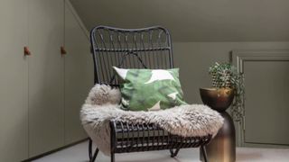 Gray green bedroom with a black woven chair with leaf-print cushion to show bedroom trends 2023