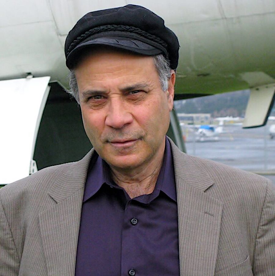 A man in a cap standing in front of an airplane