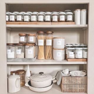 Organized kitchen storage featuring rustic labeled glass jars for dried goods and spices.