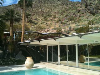 Garden view of pool with mirrored glass wall and canopies