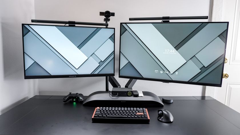A dual-monitor desk setup with the SmallRig Camera Desk Mount holding up a webcam behind the displays