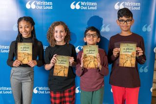 A group of four Written Out Loud graduates are pictured with the book they published as part of the program.