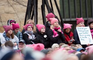 a group of women wearing pink hats at a womens march