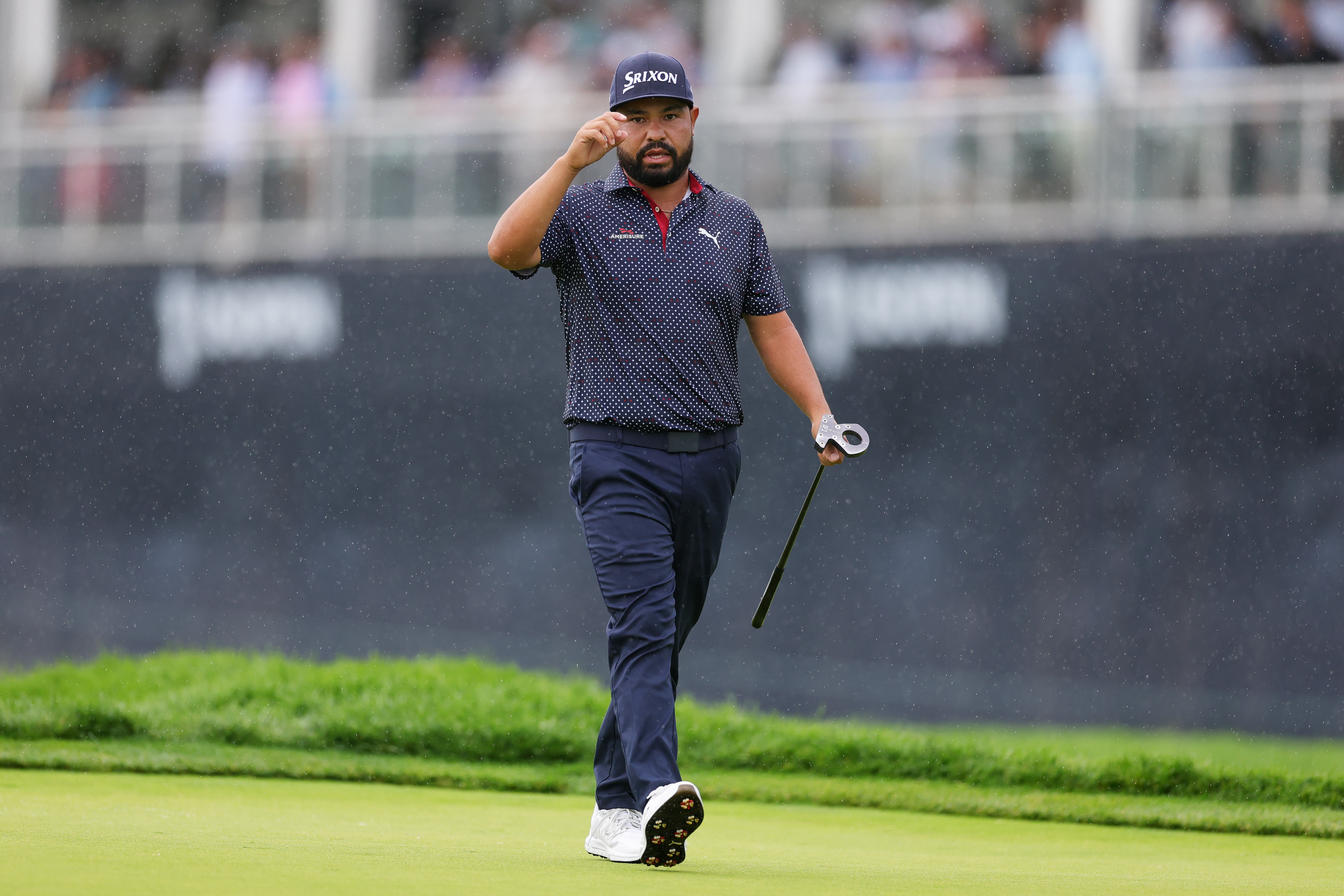 JJ Spaun taps his cap as he walks on the 18th green