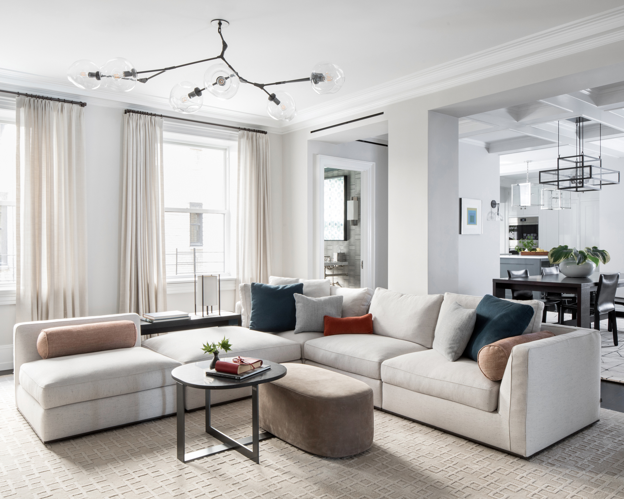 A living room with grey corner sofa, white walls and contemporary chandelier