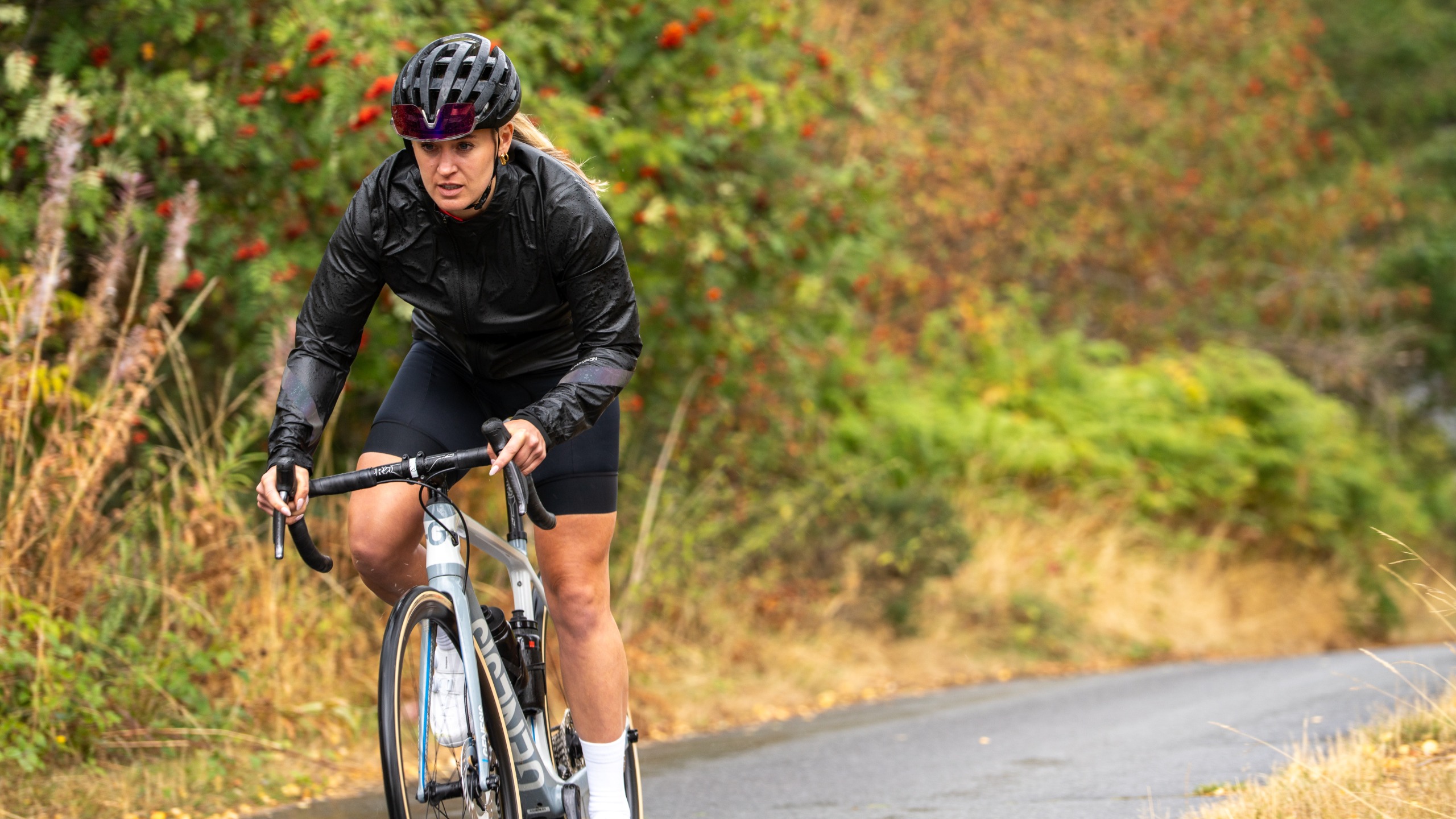 A female cyclist wearing a black Madison Hydroshift waterproof jacket 
