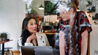 Two women talking in a cafe about confidence boosters