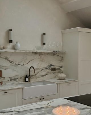 A kitchen with limewash walls and marble backsplash