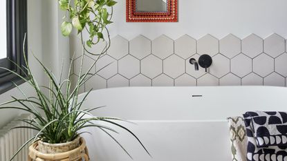 White bath with hexagonal white tiles on wall 