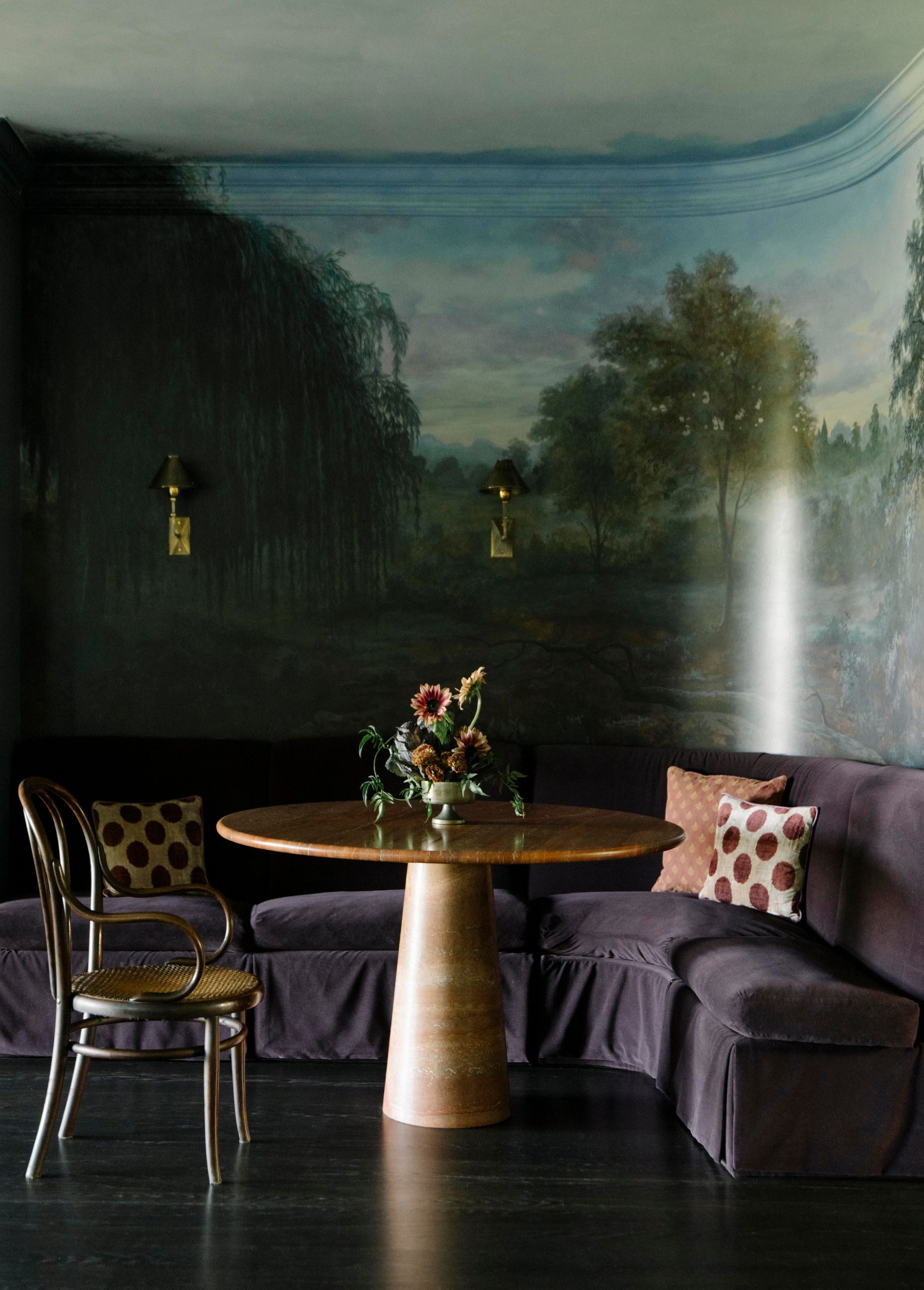 A nook with velvet sofa, contemporary brass and stone table and antique wooden chair