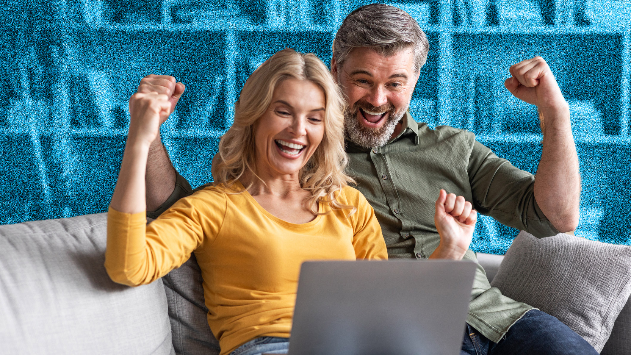 Couple sitting on sofa with a laptop and looking excited.