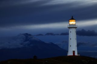 Lighthouse in front of a dark cloudy background