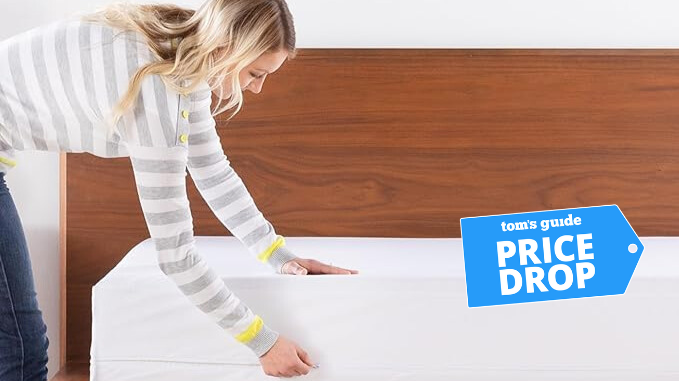 Woman fixing a white mattress protector on the bed with a brown headboard