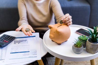 Woman's hand putting a coin into a ceramic piggy bank