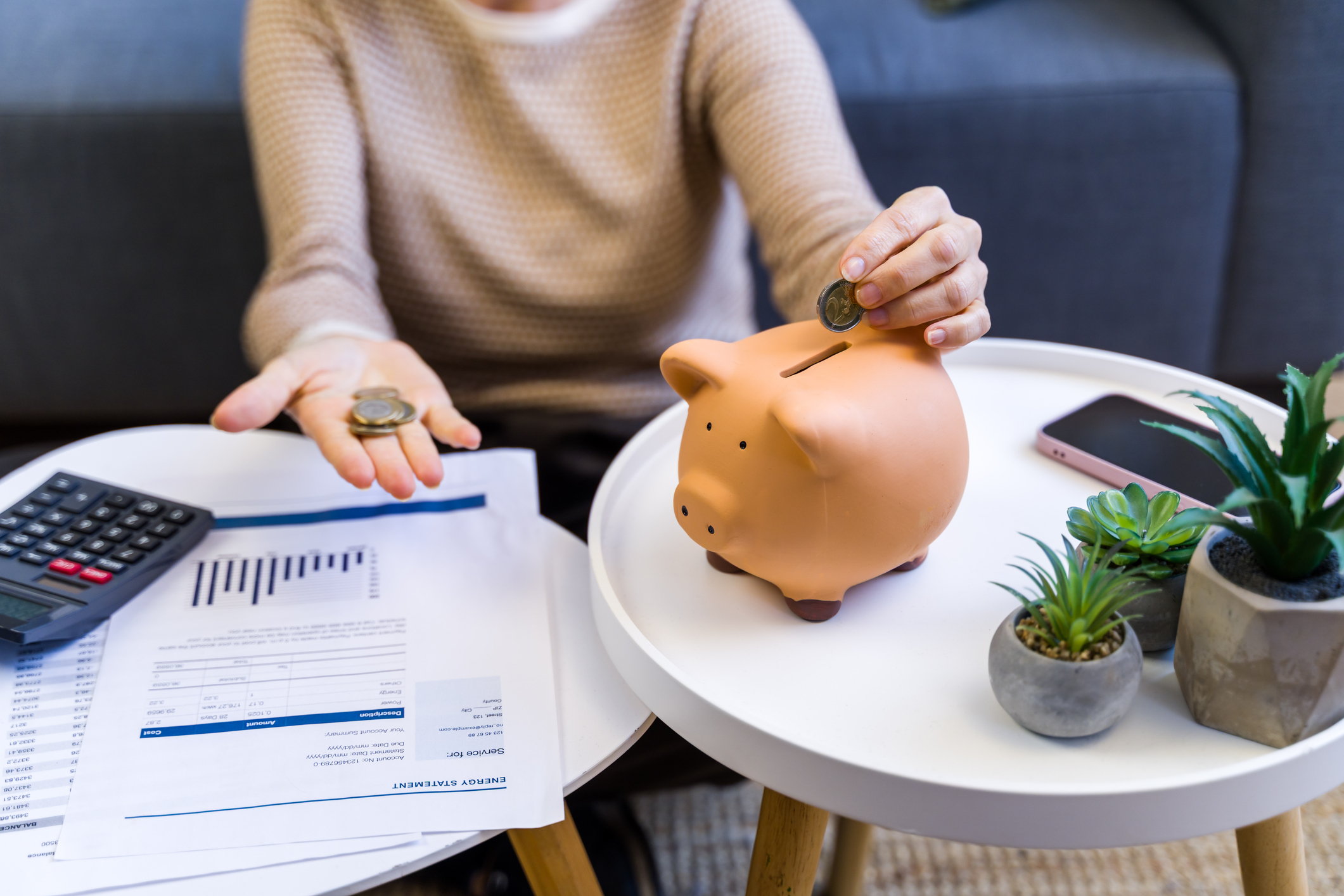 Woman's hand putting a coin into a ceramic piggy bank