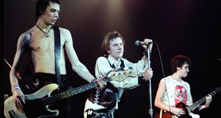 A shirtless Sid Vicious stands in line with fellow Pistols Johnny Rotten and Steve Jones, who plays a Firebird