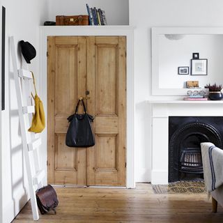 bedroom area with white wall and wooden door with mirror and handbag