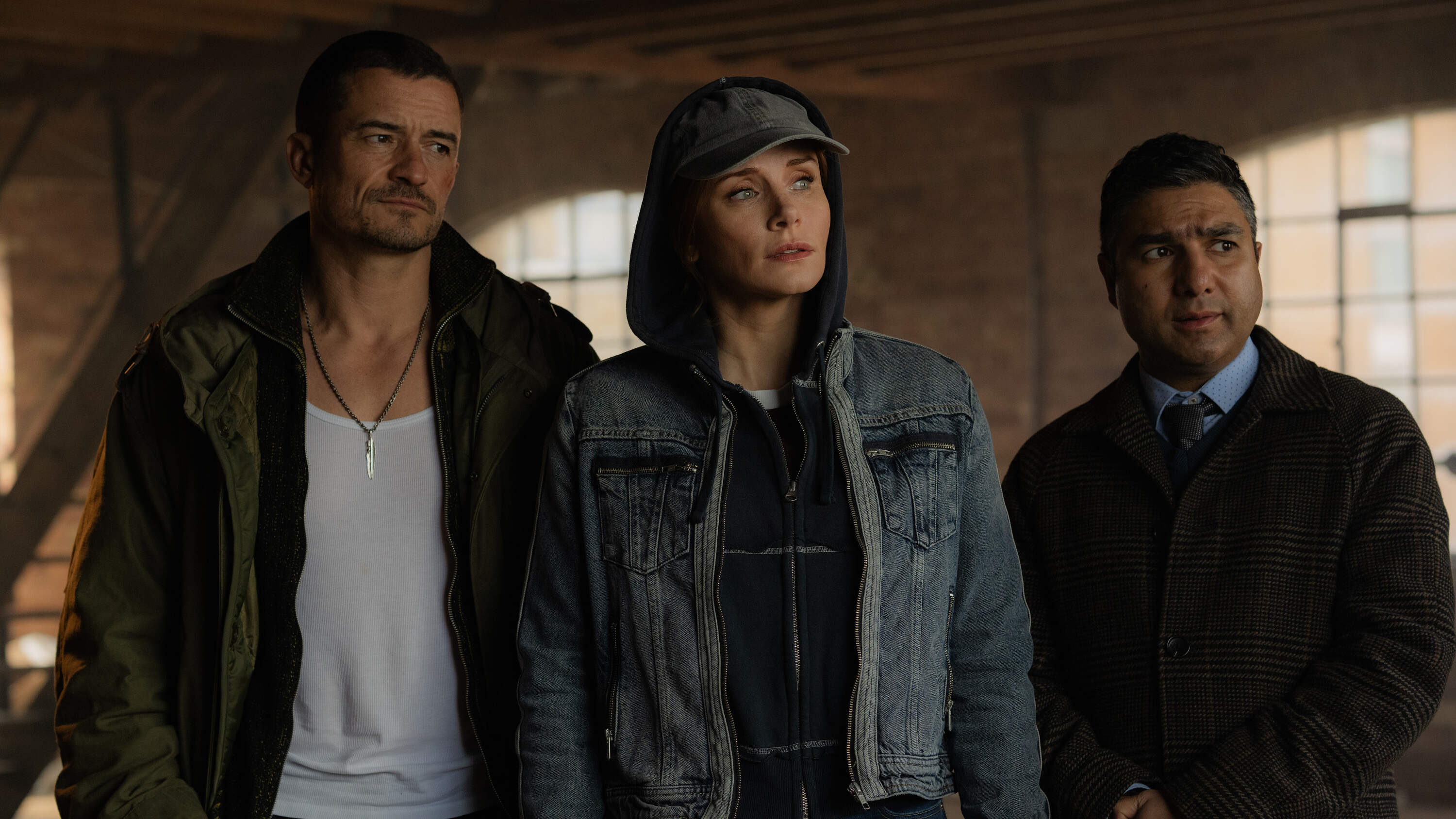 L-R: Marlon (Orlando Bloom), Kat (Bryce Dallas Howard) and Hugh (Nick Mohammed) standing together in a scene from Prime Video's "Deep Cover"