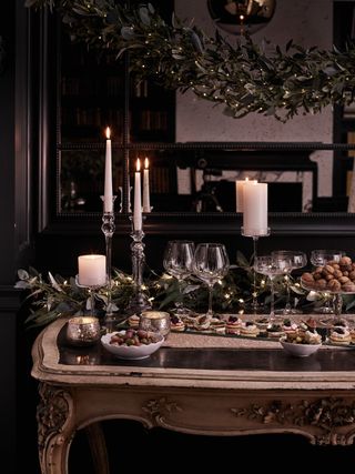 Console table with festive food, festive table garland and hanging garland above