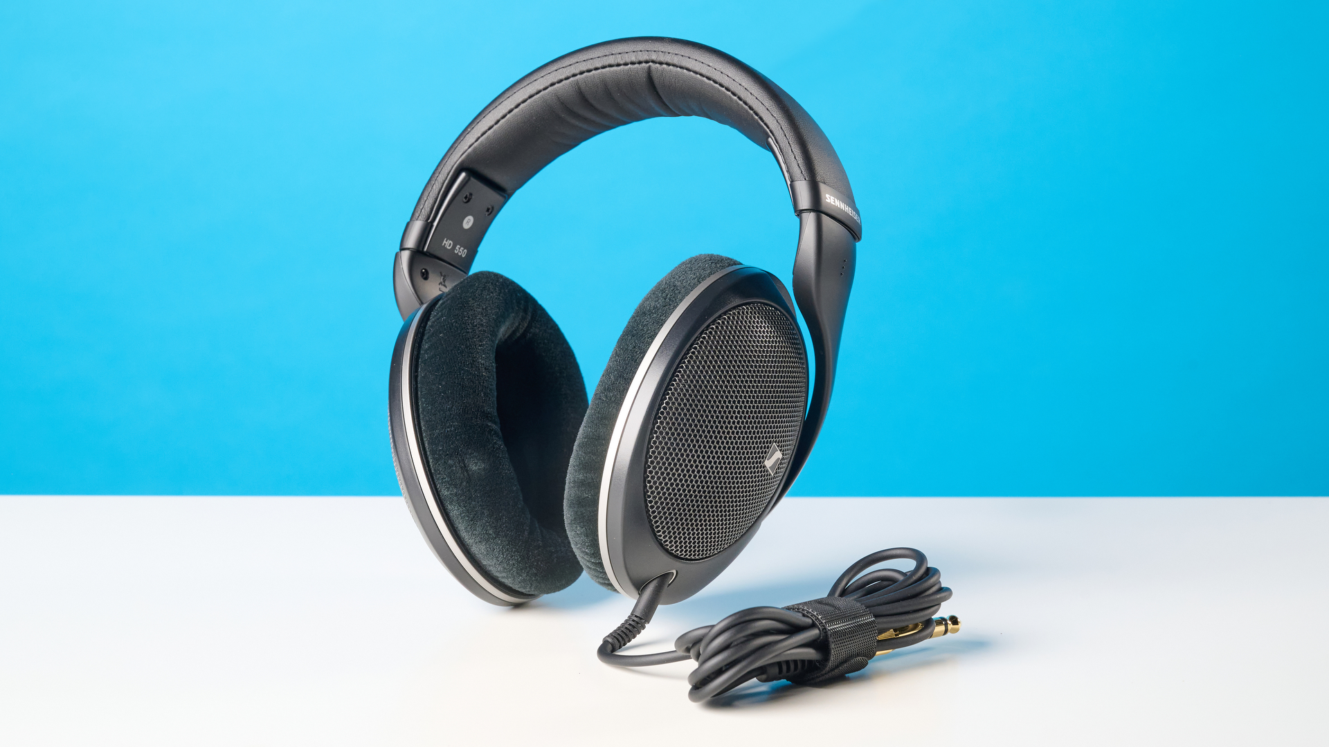 The Sennheiser HD 550 headphones on a stone surface with a blue background
